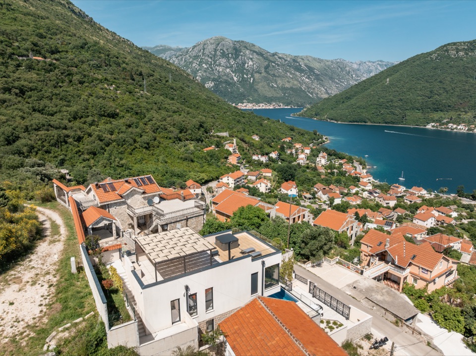Red rooftops of a coastal village below the mountains