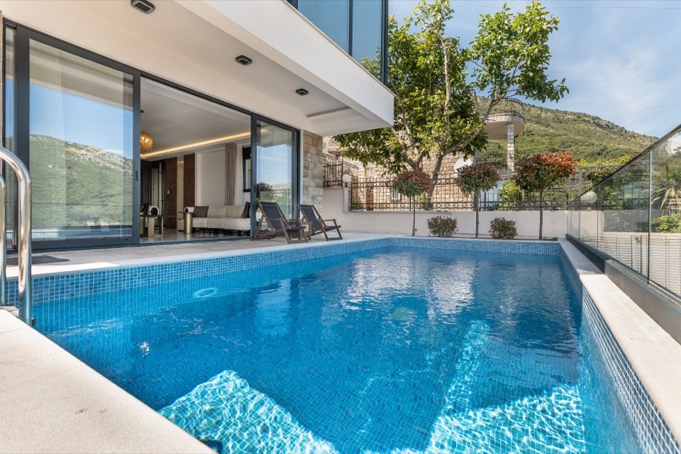 The villa pool at dusk, sliding doors open