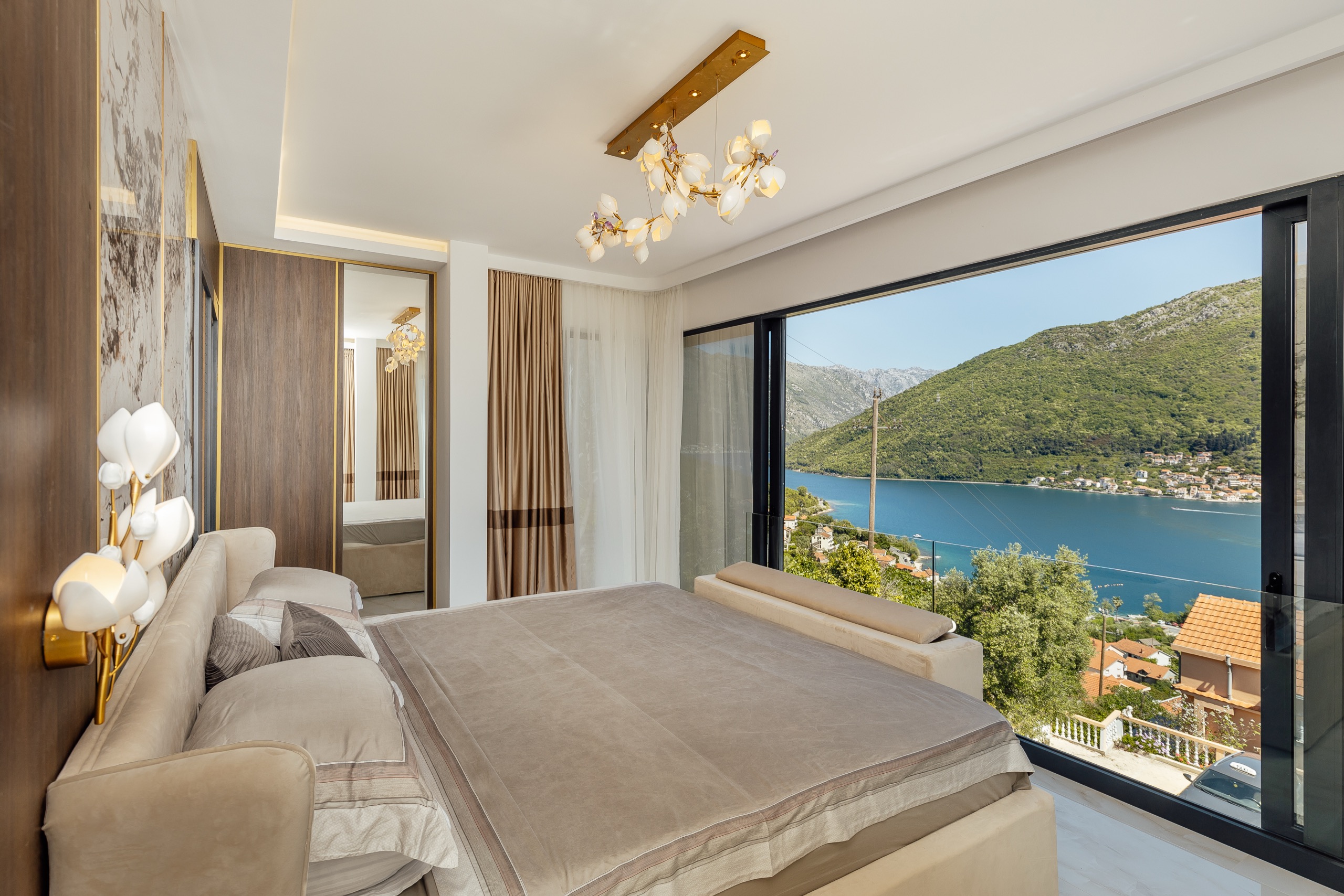 A bedroom opening onto the bay through full-height glass