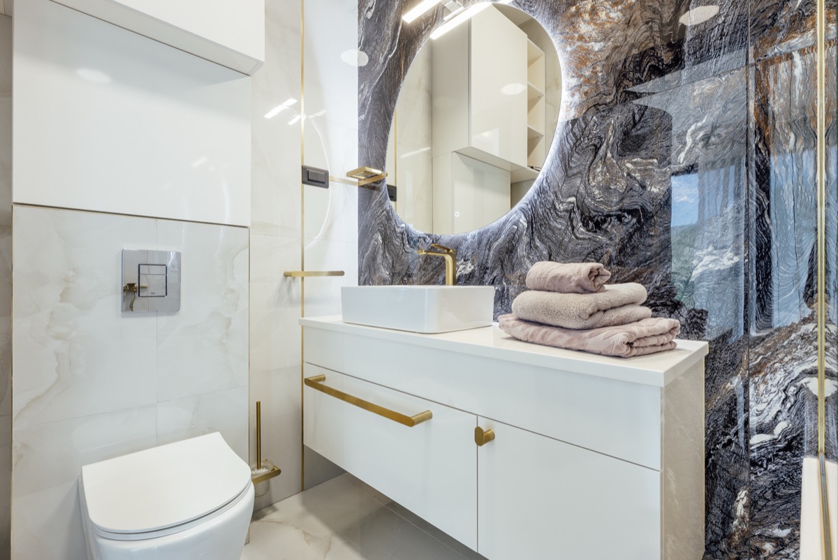 The bathroom with a round mirror and stone basin