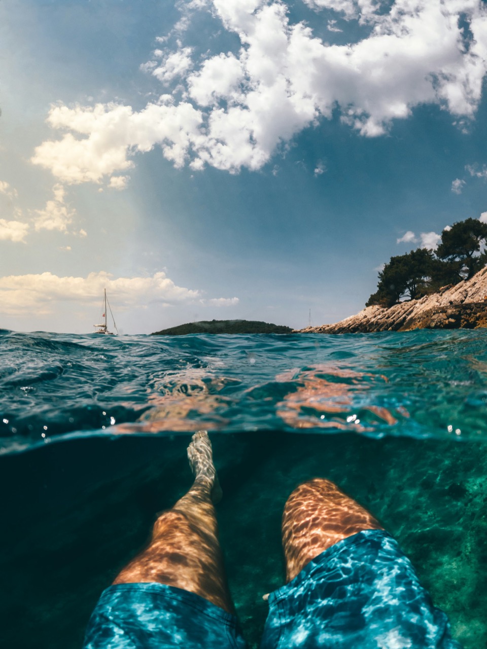 Floating in the clear water of the bay, seen half above and half below the surface